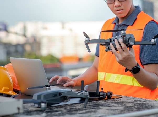 man holding a disassembled drone with a computer