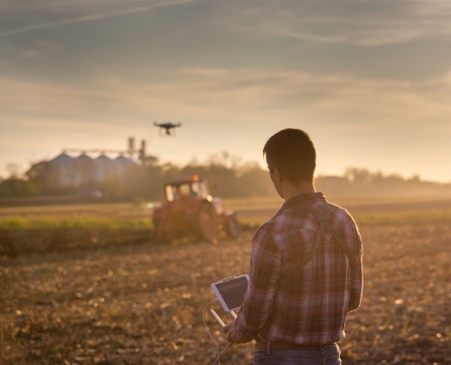 Man in a field using a drone to survey agriculture operations on a farm