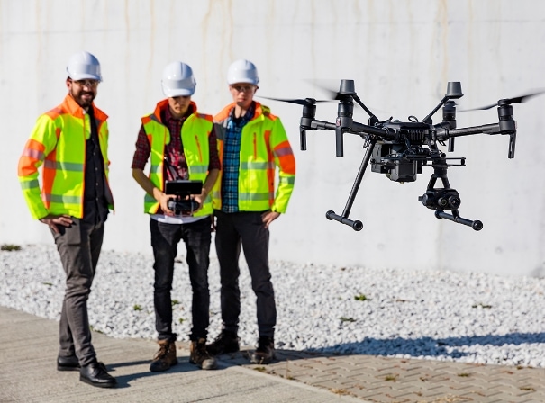 men flying drone in safety jackets