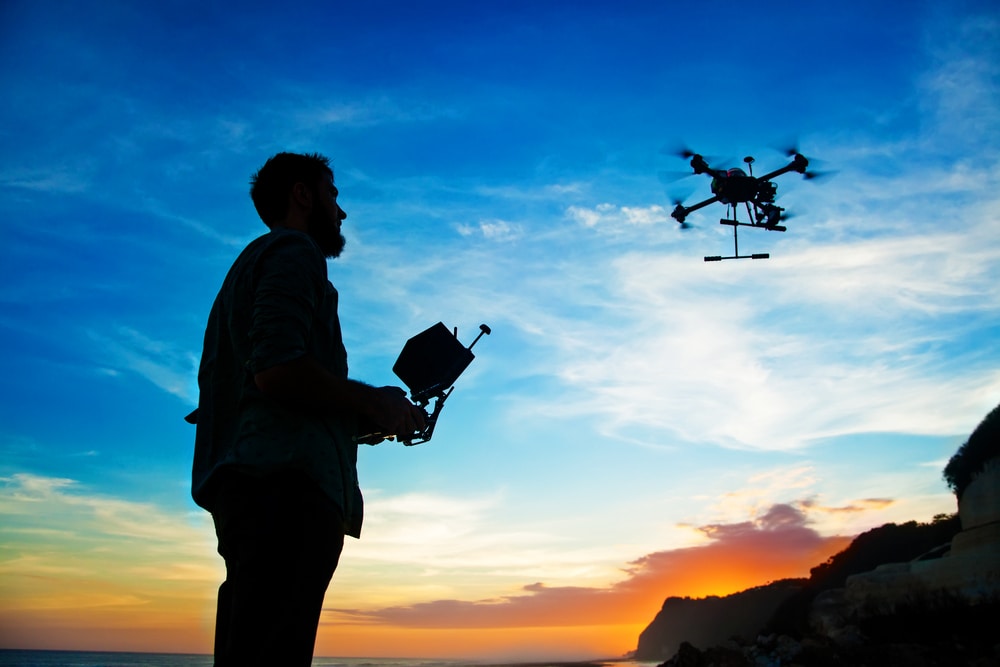 Man testing Drone with Silhouette against the Sunset Sky